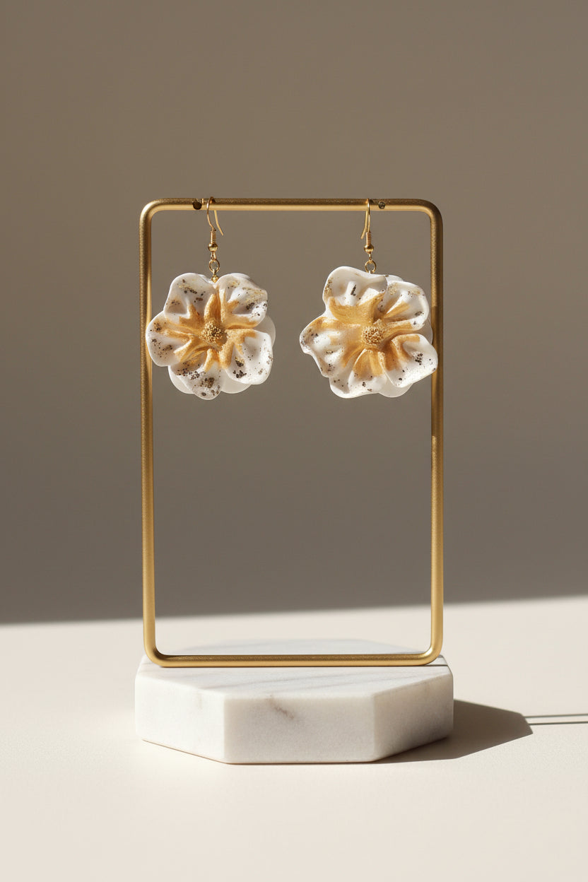 Ces boucles d'oreilles présentent un motif floral raffiné en blanc immaculé, rehaussé de touches dorées pour une touche de sophistication. L'argile polymère utilisée garantit une légèreté exceptionnelle tout en offrant une résistance durable