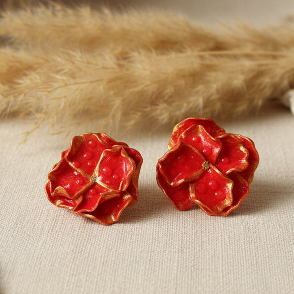 Boucles d'oreilles artisanales fleurs rouge et doré en argile polymère. Ultra-légères, uniques et élégantes. Création fait main française pour un style audacieux.