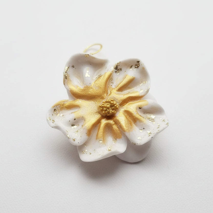 Ces boucles d'oreilles présentent un motif floral raffiné en blanc immaculé, rehaussé de touches dorées pour une touche de sophistication. L'argile polymère utilisée garantit une légèreté exceptionnelle tout en offrant une résistance durable