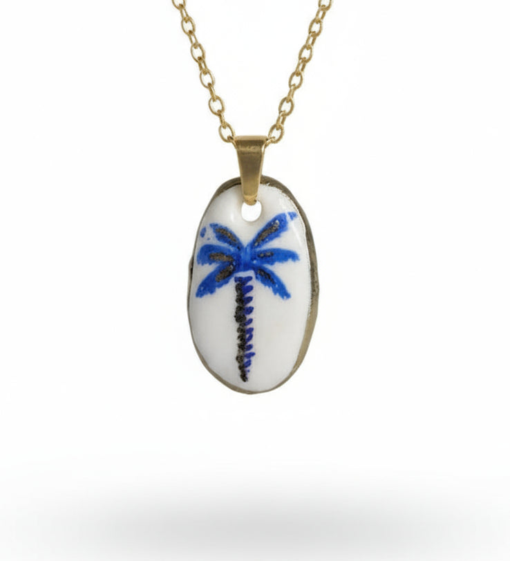 Pendentif artisanal palmier bleu et doré en argile polymère sur fond blanc