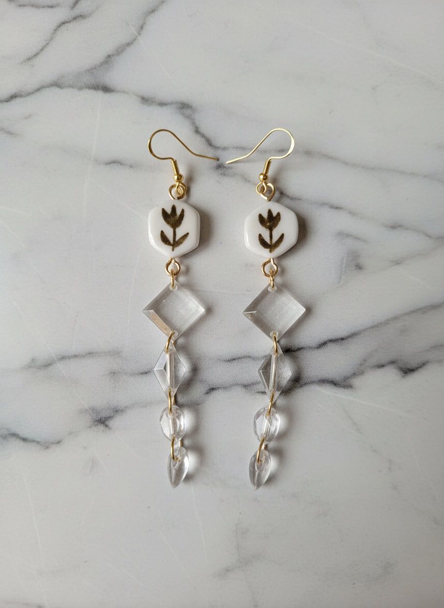 Boucles d'oreilles florales or et blanc avec pendentifs en cristal transparent et crochets dorés en acier inoxydable, style rétro chic. Bijou fait main idéal pour une soirée élégante ou une tenue vintage.